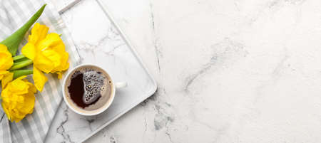 Tray with cup of coffee and flowers on light background with space for text, top viewの写真素材