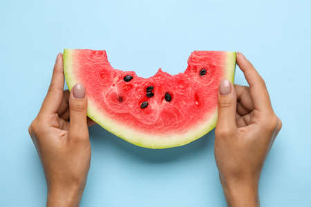 woman with slice of bitten watermelon on blue backgroundの写真素材
