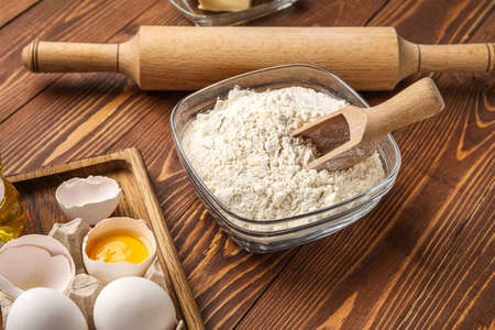 Glass bowl with flour and scoop on wooden backgroundの写真素材