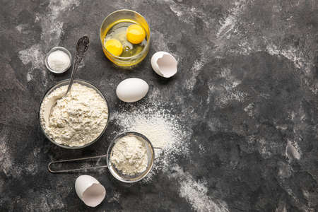 Flour and eggs on dark background
