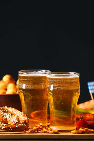 Board with glasses of beer and food on table against dark background. Oktoberfest celebrationの写真素材