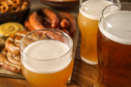 Mugs of fresh beer and traditional food on wooden background, closeup. Oktoberfest celebrationの写真素材