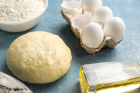 Raw dough, eggs and bottle of oil on color background, closeupの写真素材