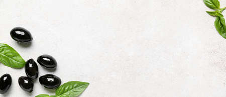 Tasty black olives and basil on light background with space for textの写真素材