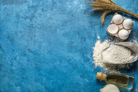 Bottle of oil, flour and eggs on color background