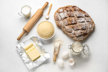 Fresh rye bread with raw dough, ingredients and utensils on white backgroundの写真素材