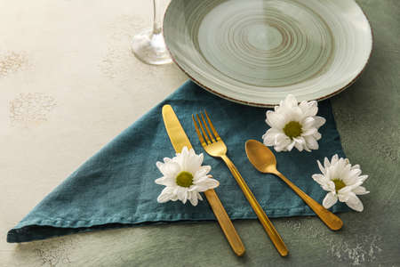 Table setting with chamomile flowers on white and green background