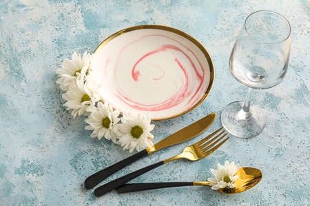 Stylish table setting with chamomile flowers on blue background