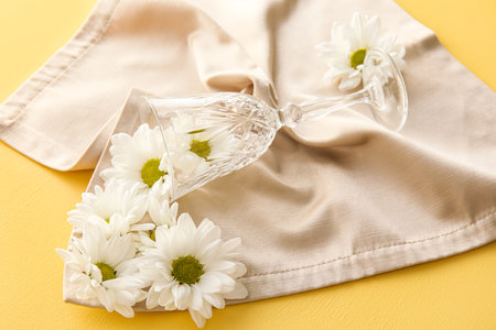 Glass, napkin and chamomile flowers on yellow backgroundの写真素材