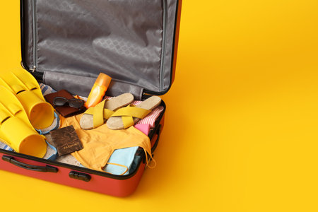 Suitcase with beach accessories and passport on yellow backgroundの写真素材