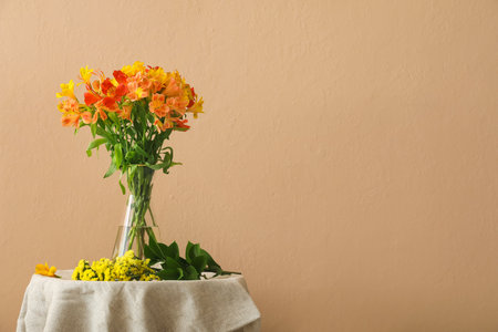 Beautiful alstroemeria flowers on table near beige wallの写真素材