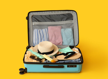 Open suitcase with beach accessories and clothes on color backgroundの写真素材
