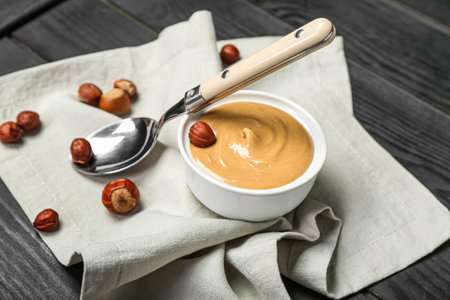 Bowl of tasty hazelnut butter and nuts on dark wooden background, closeupの写真素材