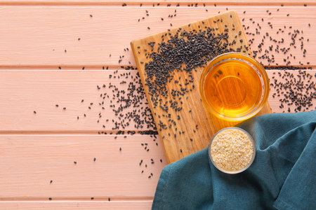 Board with bowls of sesame seeds and oil on color wooden backgroundの写真素材