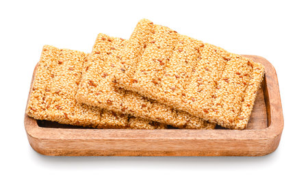 Wooden board with tasty sesame kozinaki on white backgroundの写真素材