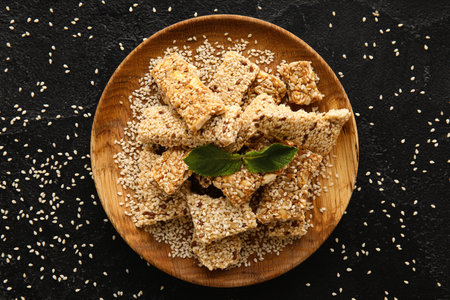 Plate with pieces of tasty sesame kozinaki on dark background