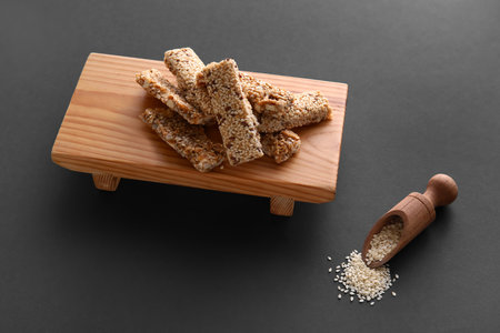 Wooden board of tasty kozinaki with sesame seeds on dark backgroundの写真素材