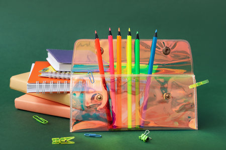 Holographic pencil case with school stationery on green background