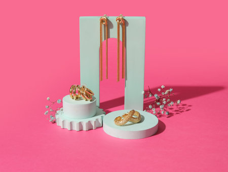 Showcase pedestals with trendy earrings and gypsophila flowers on pink backgroundの写真素材