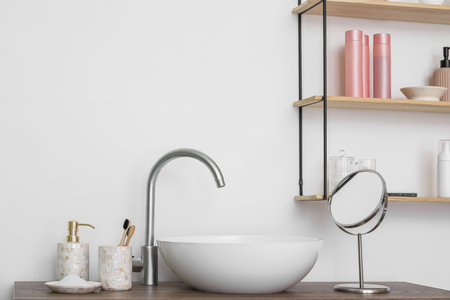 Modern sink and bath accessories on table near white wallの写真素材