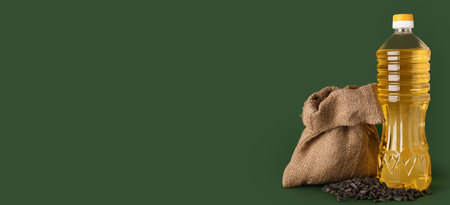 Bottle of sunflower oil and seeds on green background with space for text