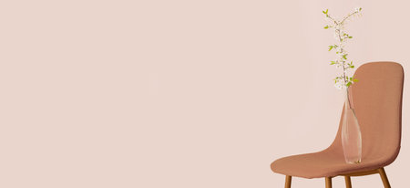 Vase with beautiful blooming branch on chair against beige background with space for textの写真素材
