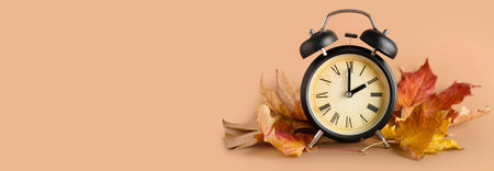 Alarm clock and autumn leaves on brown background with space for text