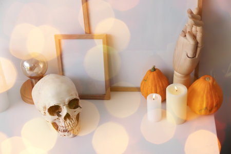Blank frames with Halloween decorations on shelf near light wall in roomの写真素材