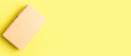 Blank cardboard box on yellow background with space for text, top view