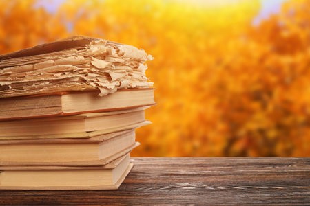 Stack of old books on wooden table outdoors on autumn dayの写真素材