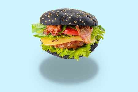 Tasty fresh burger with black bun on light blue backgroundの写真素材