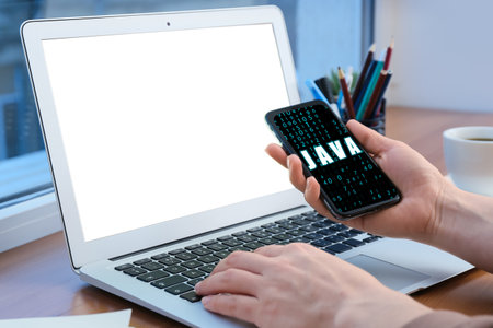 Female programmer with modern mobile phone and laptop in office