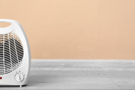 Electric fan heater near beige wallの写真素材