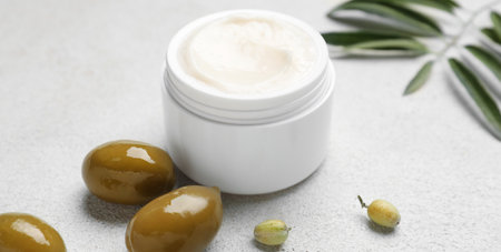 Jar of cream with olive oil extract on light background, closeup