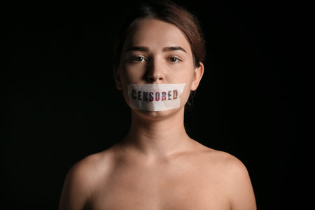 Woman with taped mouth on dark background. Censorship conceptの写真素材