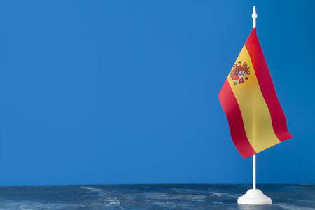 Flag of Spain on table against blue background
