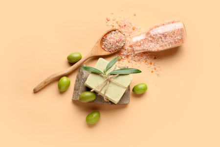 Soap bar, bottle of sea salt and green olives on color backgroundの写真素材