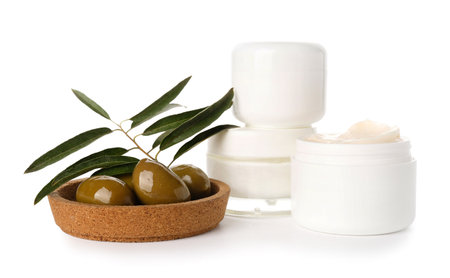 Jars with natural cream and plate of green olives on white backgroundの写真素材