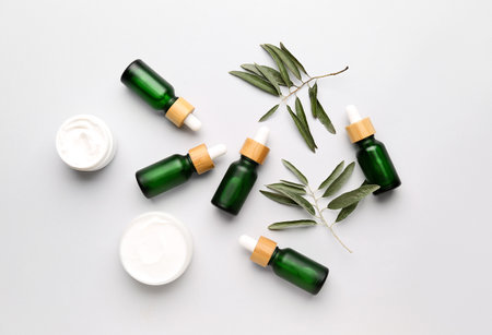 Bottles of essential olive oil and jars with cream on white backgroundの写真素材