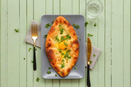Plate with tasty Ajarian khachapuri on color wooden backgroundの写真素材