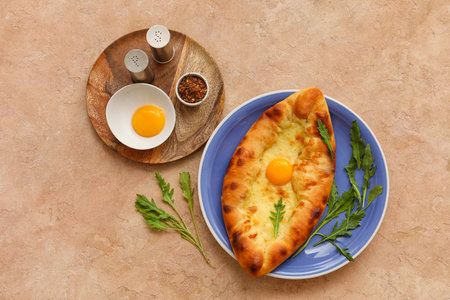 Plate with tasty Ajarian khachapuri, arugula and spices on color backgroundの写真素材