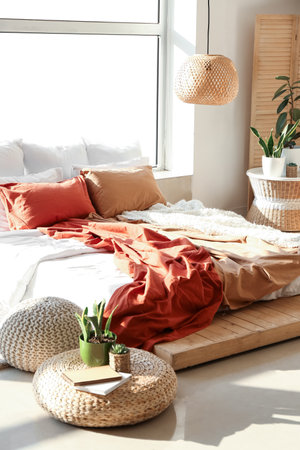 Interior of light room with big bed and green houseplants