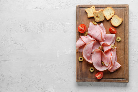 Wooden board with tasty ham on light background