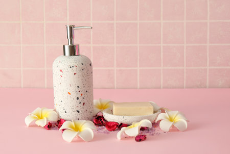 Bath accessories with flowers on table near pink tile wallの写真素材