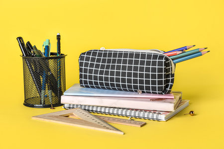 Checkered pencil case with school stationery on yellow background