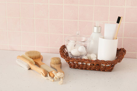 Bath accessories with massage brushes on table near pink tile wall