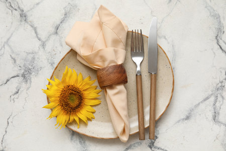 Simple table setting with cutlery, napkin and sunflower on white marble backgroundの写真素材