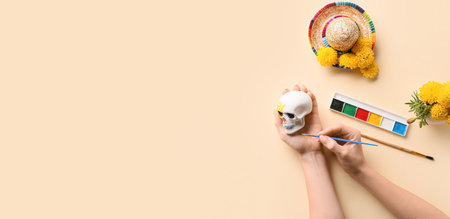 Woman painting skull for Mexico's Day of the Dead (El Dia de Muertos) on beige background with space for text, top viewの写真素材