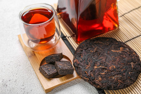 Board with dry pressed puer tea and glass on white background, closeupの写真素材