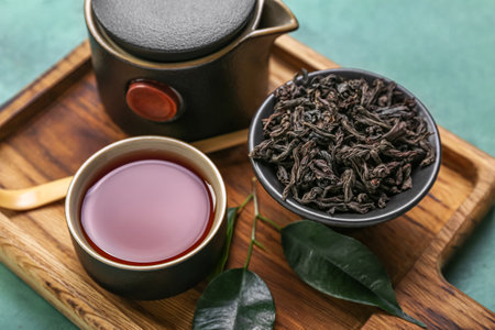 Board with bowl of dry puer tea, cup and teapot on grunge background, closeupの写真素材